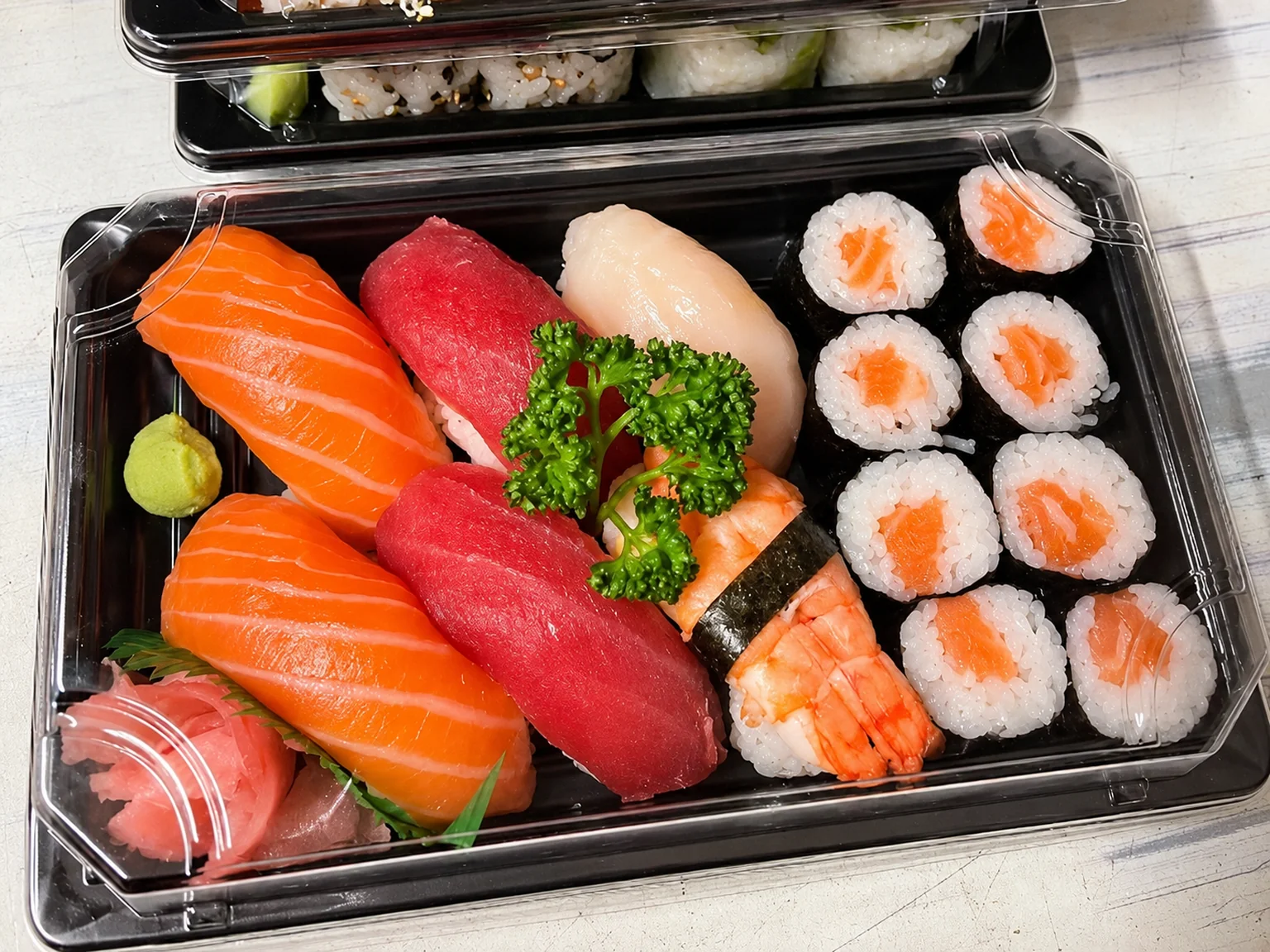 Sushi and maki in a black box with a clear lid.