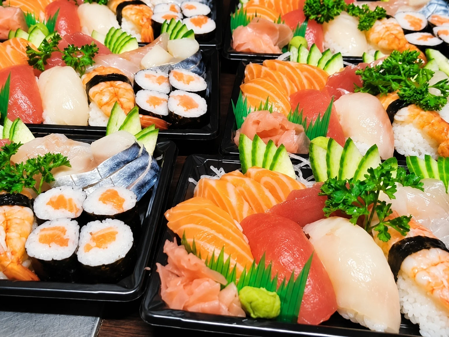 Sushi, sashimi and maki in black boxes.
